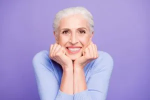 A smiling older woman on a purple background