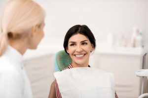 A female patient smiles in a dental chair