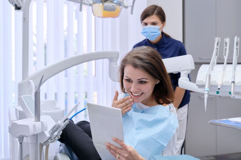 a smiling dental patient looks in a mirror
